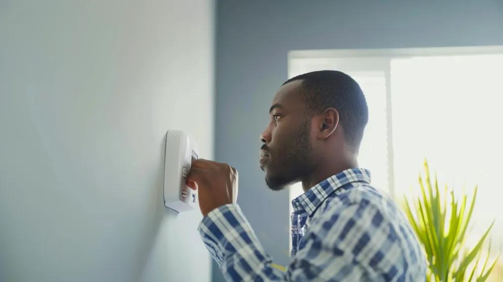 Homeowner adjusting thermostat